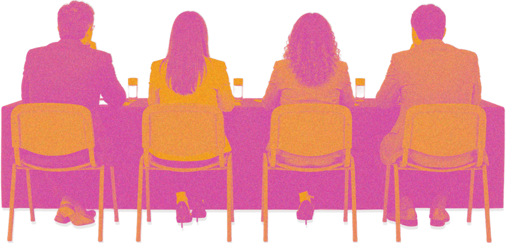Four people seated in a row at a conference table, seen from behind, with drinks in front of them on a meeting or panel setting